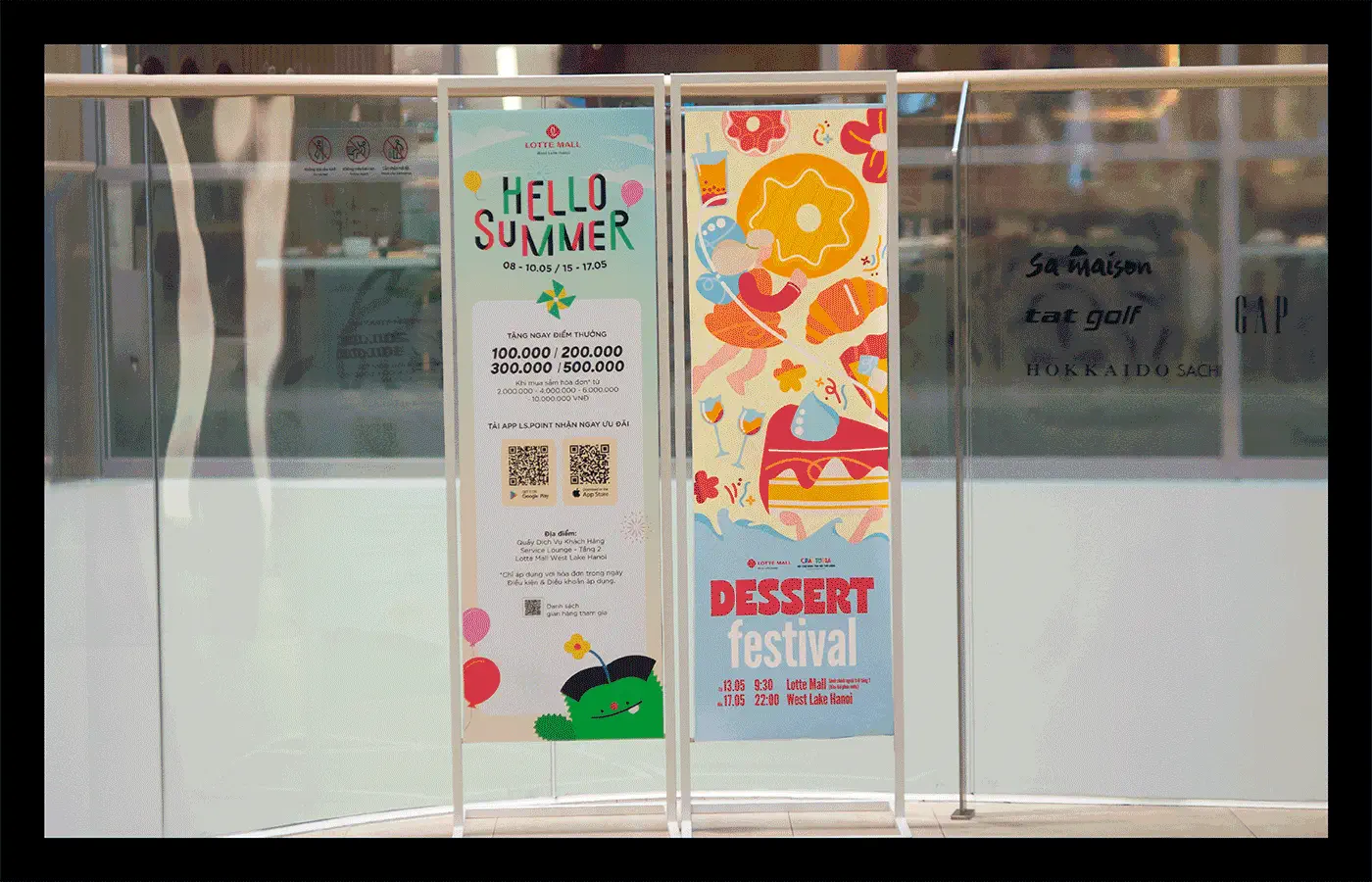 Photograph of two tall storefront posters reading HELLO SUMMER and DESSERT festival.